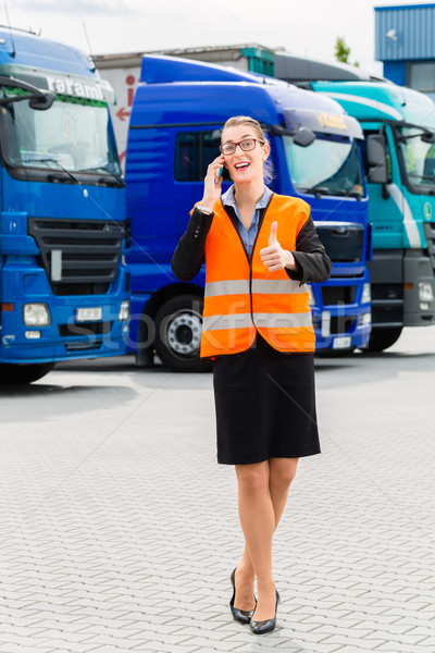 Stock photo: Female forwarder in front of trucks on a depot