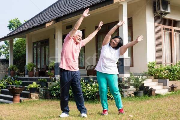 Active senior couple exercising with raised arms outdoors Stock photo © Kzenon