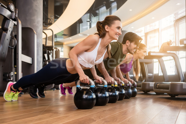 Three young people doing the kettlebell plank challenge during g Stock photo © Kzenon