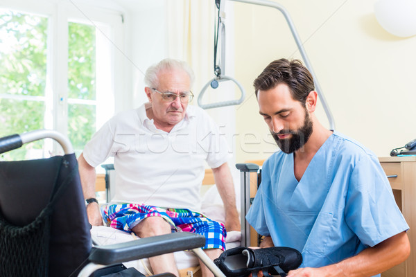 Elderly care nurse helping senior from bed to wheel chair  Stock photo © Kzenon