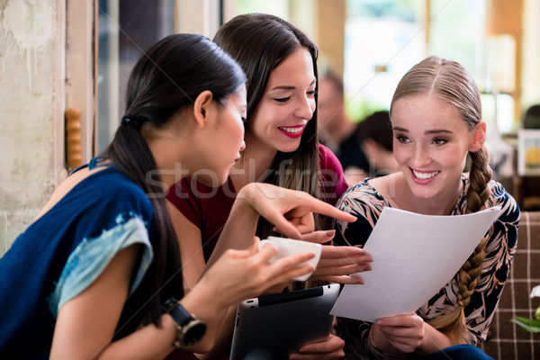Young woman showing paperwork to her friends Stock photo © Kzenon