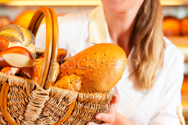 Female baker in bakery selling bread by basket  Stock photo © Kzenon