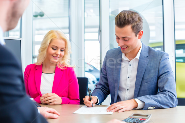 Man signing sales contract for auto at car dealership  Stock photo © Kzenon