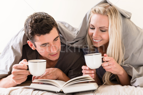 Young couple reading a book together in bed Stock photo © Kzenon