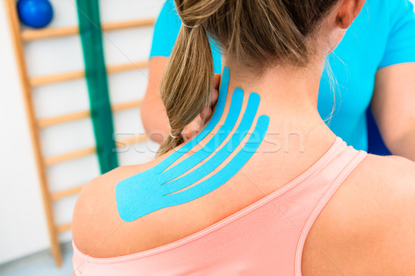 Woman from behind with Kinesio tape on shoulder in physiotherapy Stock photo © Kzenon
