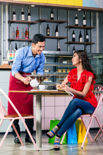 Handsome waiter serving coffee at the table of two beautiful women Stock photo © Kzenon