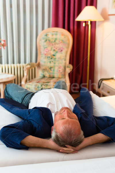 Senior man lying on the bed in the hotel room Stock photo © Kzenon