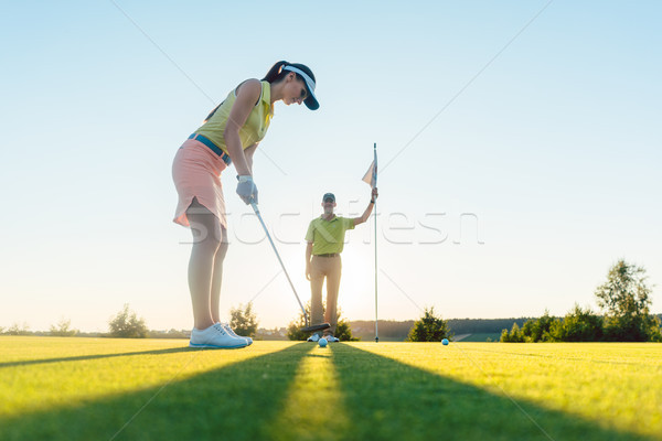Fit woman exercising hitting technique during golf class with an Stock photo © Kzenon