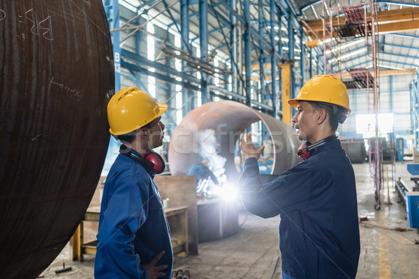 Stock photo: Two Asian experts talking while supervising fabrication