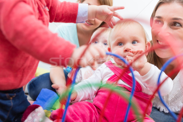 Group of happy young mothers watching their cute and healthy babies play Stock photo © Kzenon