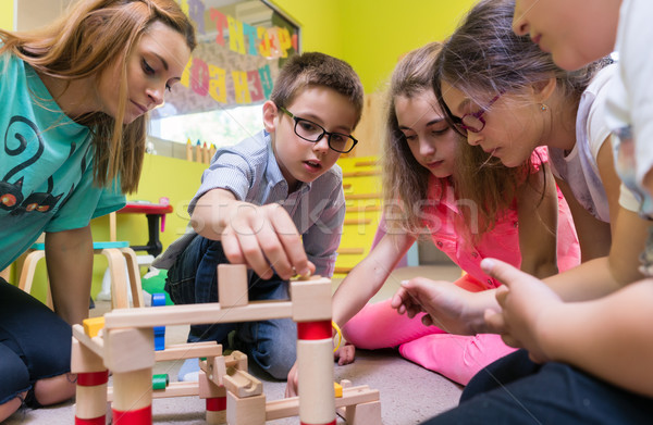 Dedicated kindergarten teacher helping children with the construction of a train Stock photo © Kzenon