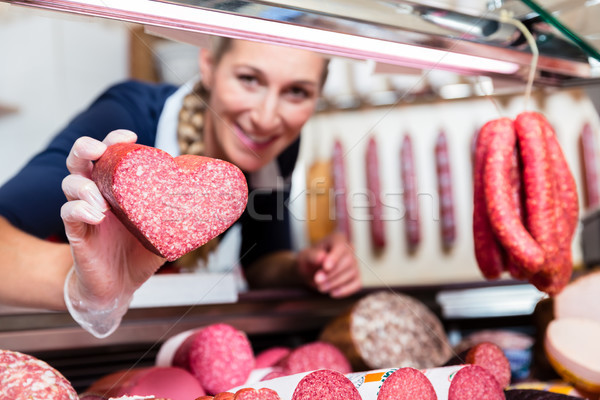 Sales woman in meat shop showing a heart shaped sausage Stock photo © Kzenon