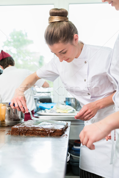 Confectioner putting chocolate as frosting on cake Stock photo © Kzenon