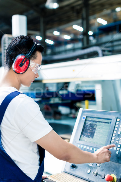 Worker entering data in CNC machine at factory Stock photo © Kzenon