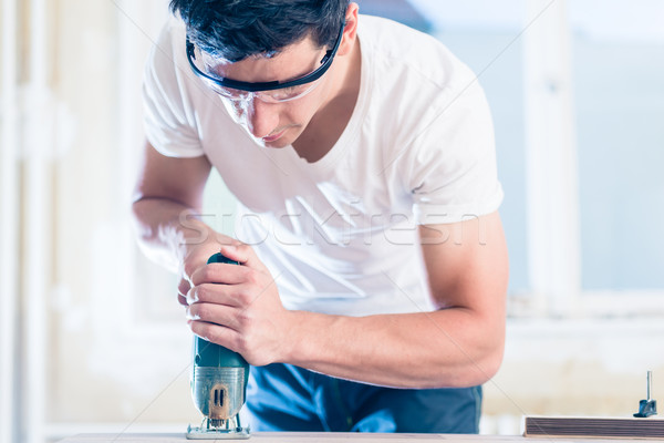 DIY worker cutting wooden panel with jig saw Stock photo © Kzenon