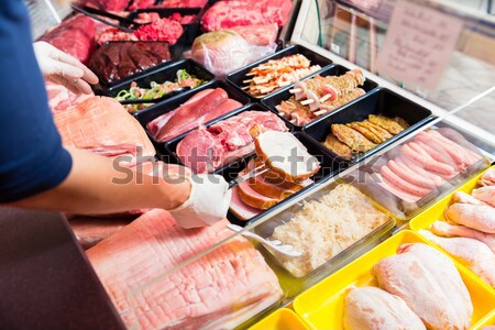 Sales woman in butchery holding sausage wrapped in paper Stock photo © Kzenon