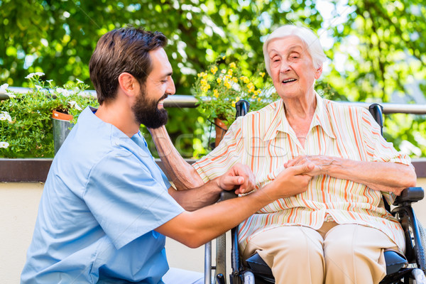 Geriatric nurse holding hand of old woman in rest home Stock photo © Kzenon