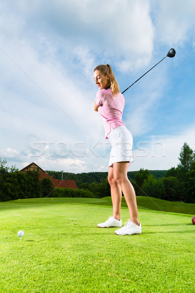 Young female golf player on course doing golf swing Stock photo © Kzenon