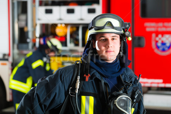 young fireman in uniform in front of firetruck Stock photo © Kzenon