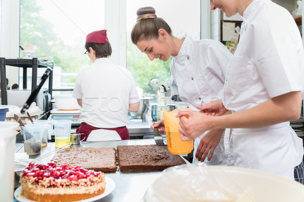 Three pastry bakers in confectionary preparing fruit pies Stock photo © Kzenon