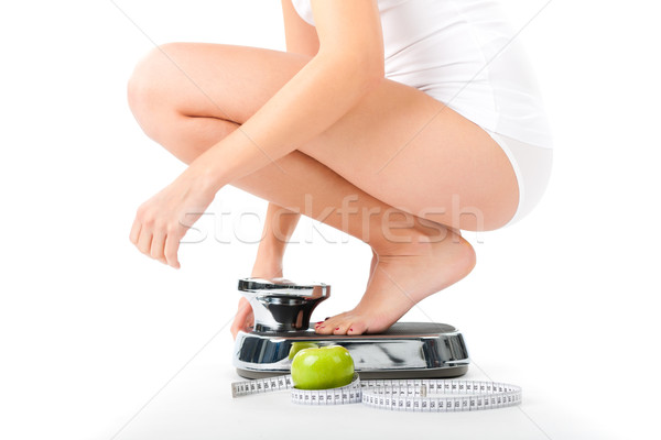 Stock photo: Young woman sitting on her haunches on a scale