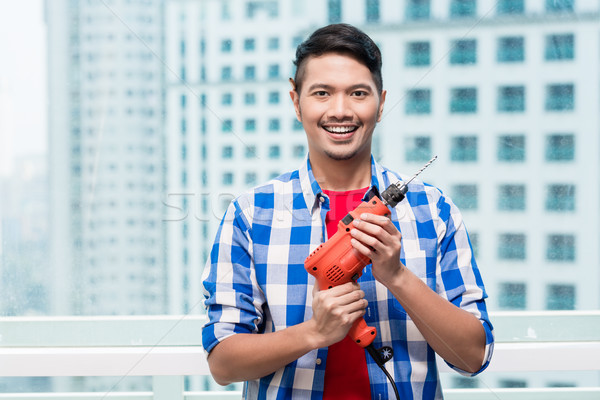 Young indonesian man with power drill Stock photo © Kzenon