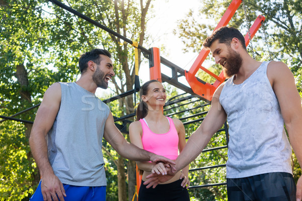 Three cheerful friends putting hands together as a gesture of motivation Stock photo © Kzenon