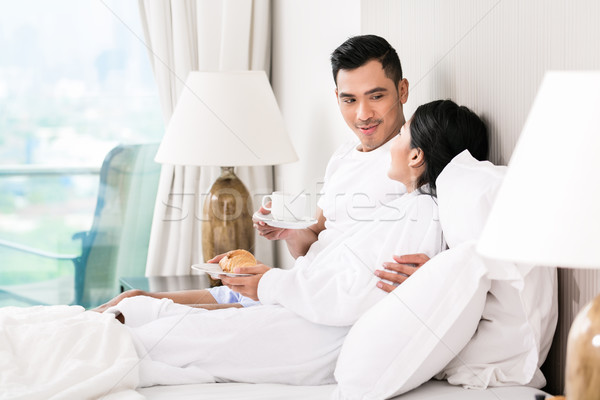 Asian couple lounging in bed at morning Stock photo © Kzenon