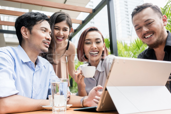 Group of four young Asian people sitting together outdoors at a  Stock photo © Kzenon