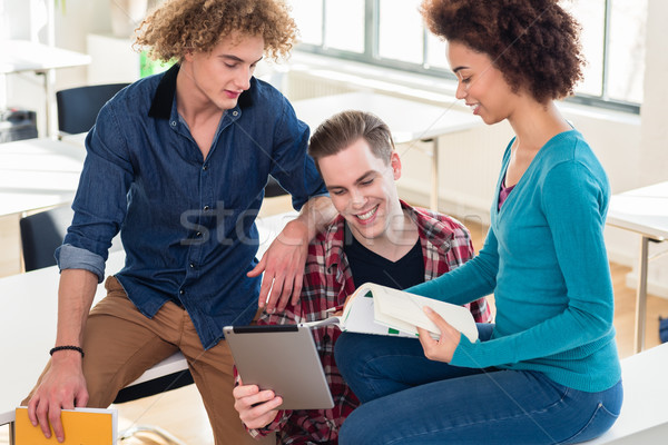 Three young students using both a book and a tablet PC for checking information Stock photo © Kzenon