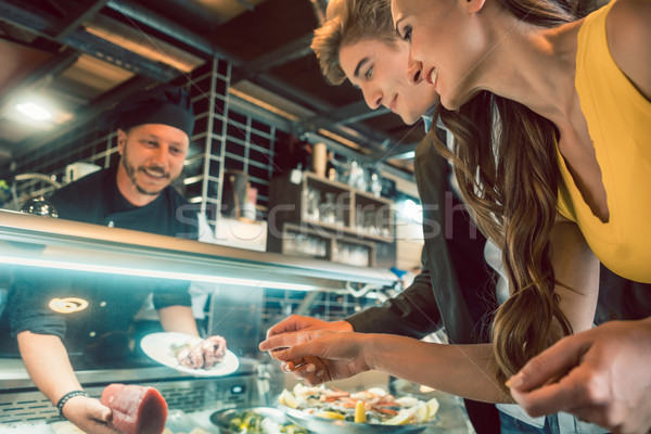 Experienced chef choosing raw seafood from the freezer for two customers Stock photo © Kzenon