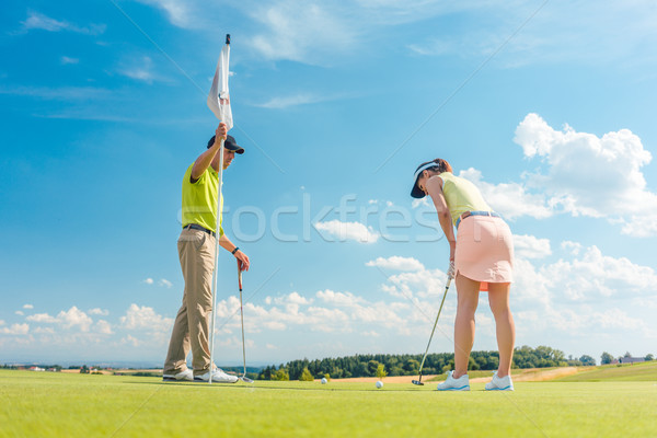 Female golf player ready to hit the ball under the instruction of a golf teacher Stock photo © Kzenon