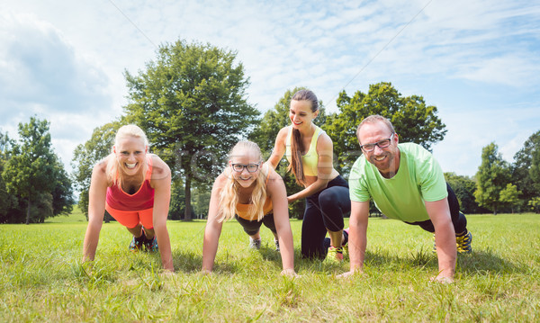 Family doing push-ups in nature under guidance by a fitness coach Stock photo © Kzenon