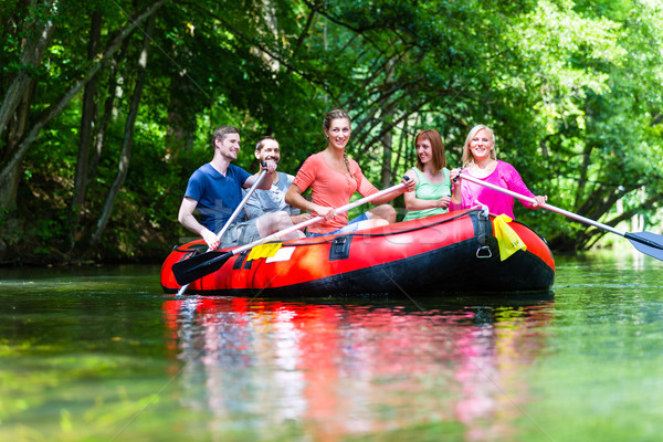 Friends paddling on rubber boat at forest river or creek Stock photo © Kzenon
