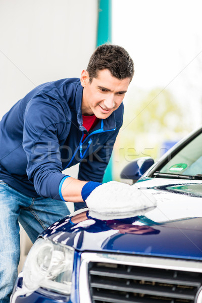 Hard-working man polishing car with white microfiber mitt Stock photo © Kzenon