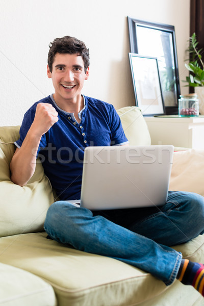 Young man looking at camera as a winner while using a laptop Stock photo © Kzenon