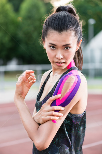 Woman taping with therapeutic tape on cinder track of sports sta Stock photo © Kzenon