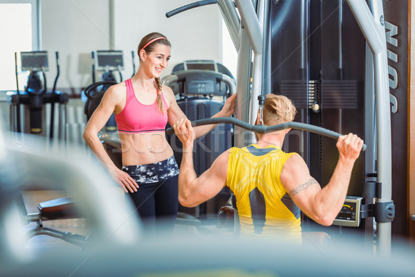 Fit beautiful woman smiling with admiration at a strong man in the gym Stock photo © Kzenon