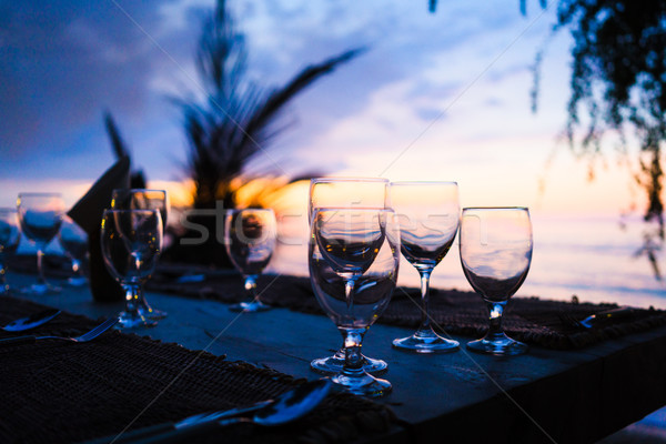 Glasses on table in tropical restaurant at sunset Stock photo © Kzenon