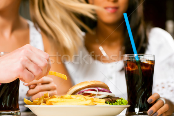 Two women eating hamburger and drinking soda Stock photo © Kzenon