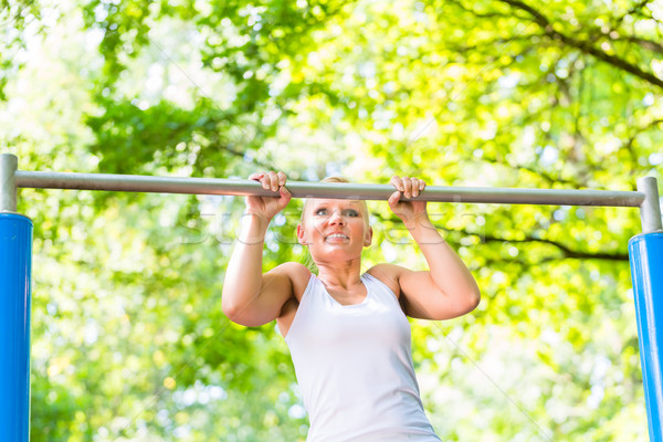 Woman exercising at high bar for better outdoor fitness Stock photo © Kzenon