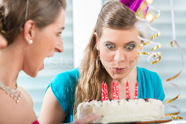 Young woman making a funny face while blowing out the candles Stock photo © Kzenon