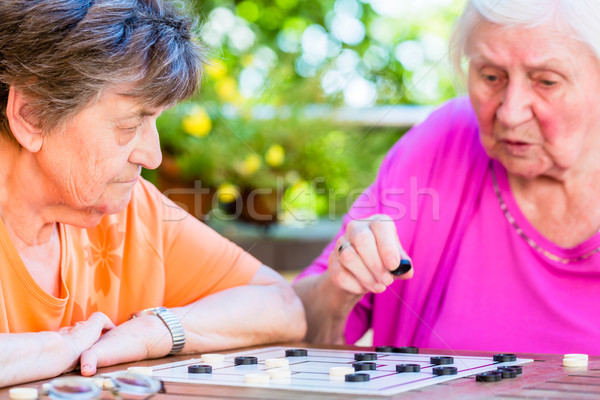 Two senior ladies playing board game in rest home Stock photo © Kzenon