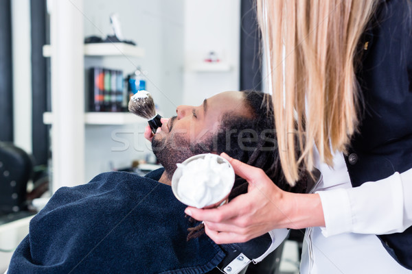 Barber soaping customer getting ready to shave him Stock photo © Kzenon