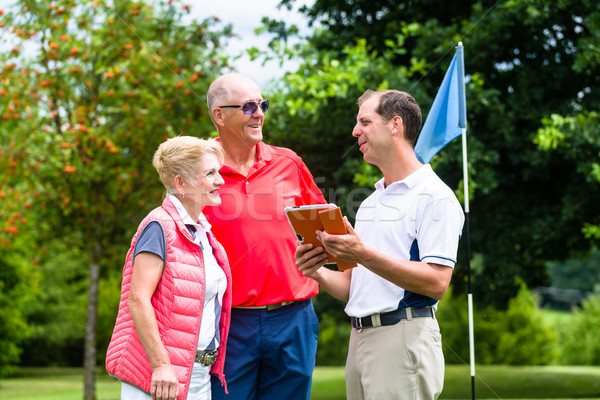 Golf pro with senior woman and man analyzing results Stock photo © Kzenon