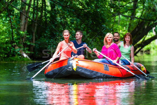 Friends paddling on rubber boat at forest river or creek Stock photo © Kzenon