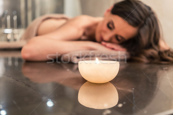 Scented candle next to young woman on marble massage table at sp Stock photo © Kzenon