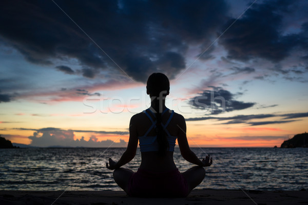 Fit woman sitting in lotus position while practicing yoga on the Stock photo © Kzenon