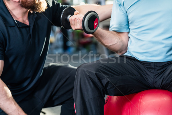 Stock photo: senior man working out with personal trainer at the gym