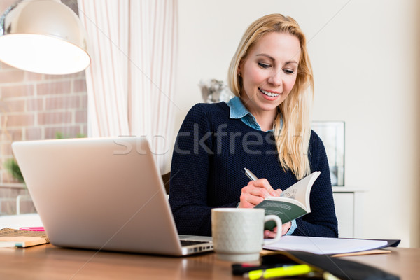 Woman at her desk writing on book Stock photo © Kzenon